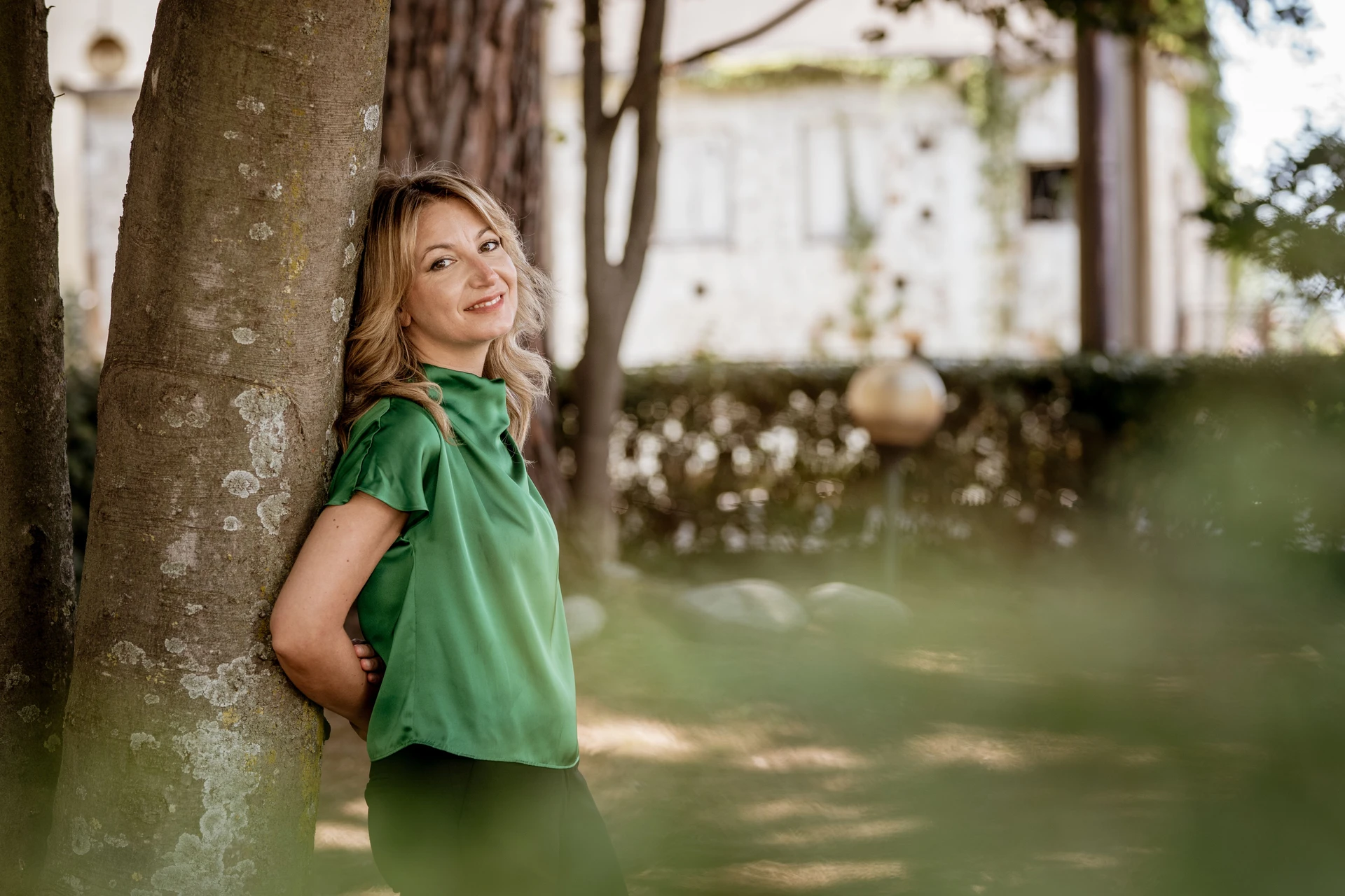 Ilaria Sinicropi leaning against a pine trunk in a garden