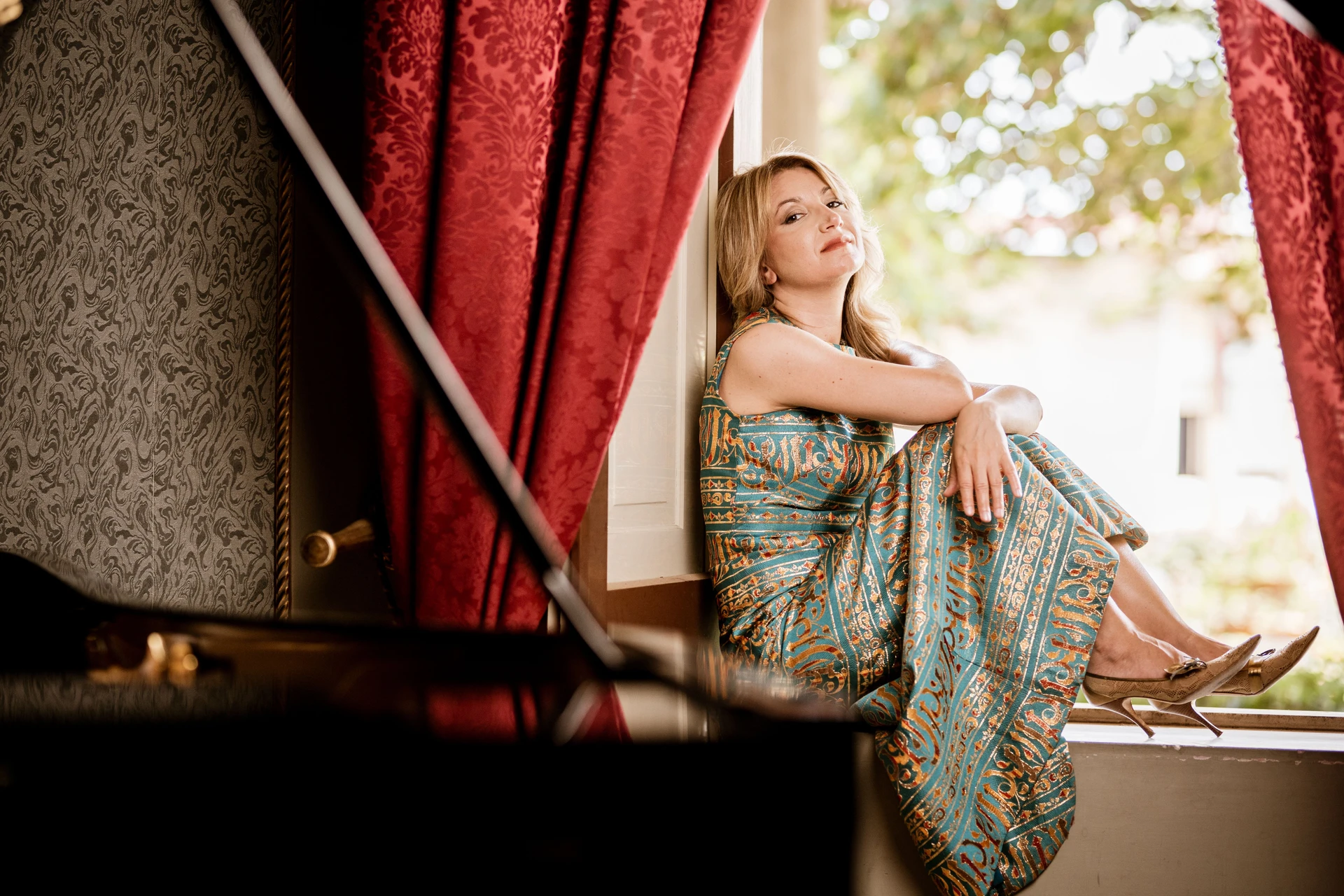 Ilaria Sinicropi sitting by a window framed by red curtains