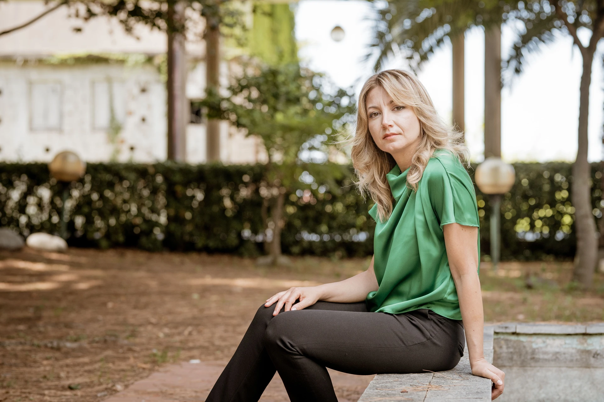 Ilaria Sinicropi sitting on a low wall in a garden